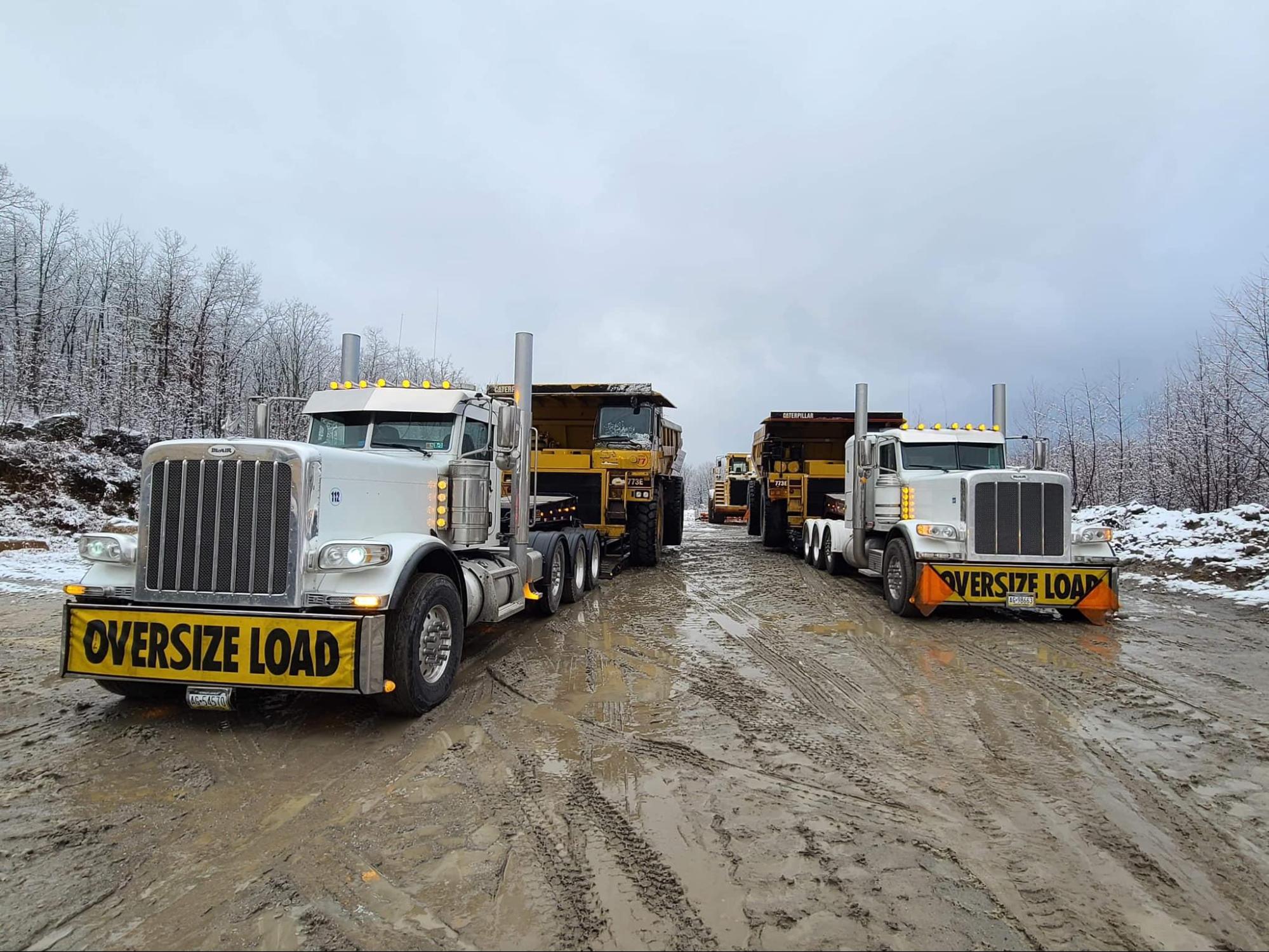 Two B. Blair oversize load trucks hauling Caterpillar dump trucks in winter